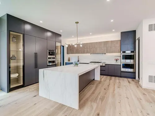 Kitchen with floor-to-ceiling graphite cabinetry, ribbed white oak uppers and a marble waterfall island