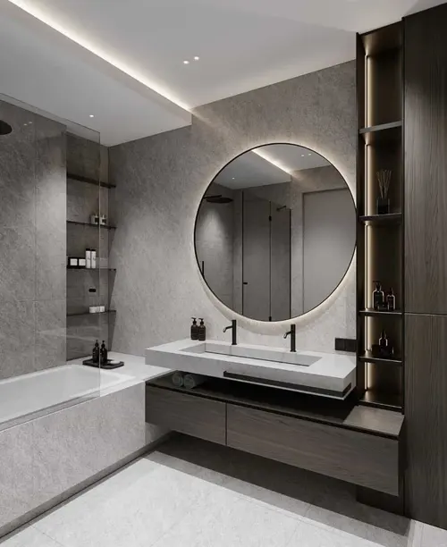 A round backlit mirror above a stone basin shelf, with a dark timber vanity and a lit niche column