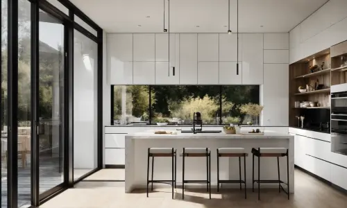 Handleless white wall units over a run of base cabinets, a stone island with four stools, and a band of glazing onto the garden